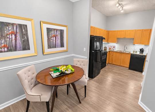 A kitchen with a table and chairs in the foreground and a refrigerator in the background.