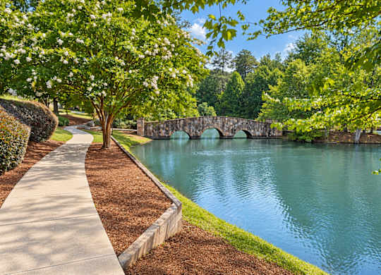 A stone bridge over a body of water with a concrete walkway on the left.
