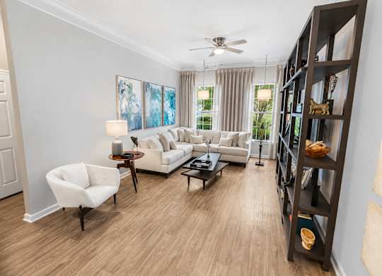 A living room with a white couch, a chair, a coffee table, and a bookshelf.
