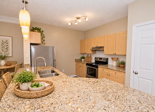 A kitchen with a granite countertop and wooden cabinets.