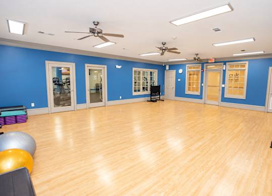 A spacious room with wooden floors and exercise equipment.