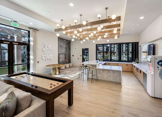 A modern kitchen with a pool table in the middle.