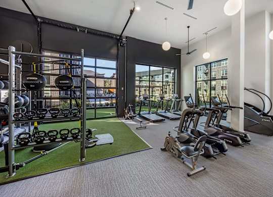 A gym with a variety of equipment including treadmills, weights, and exercise machines.