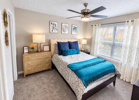 A bedroom with a bed, dresser, and ceiling fan.