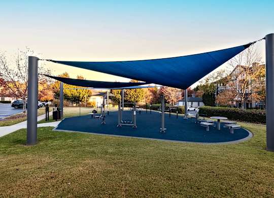 A playground with a blue canopy and a green mat.