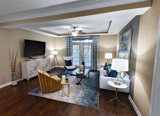 A living room with a brown chair, a white couch, and a television on the wall.