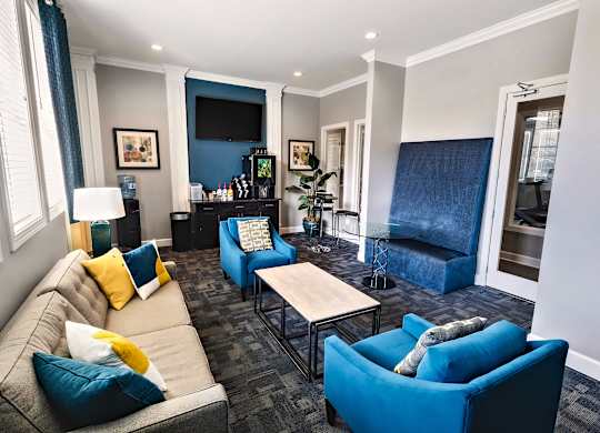 A living room with a grey couch and blue chairs.