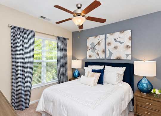 A bedroom with a white bed and a ceiling fan.