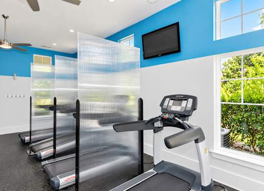 A treadmill in a room with blue walls and a fan.