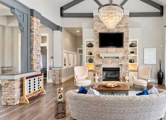 A living room with a grey couch and a stone fireplace.