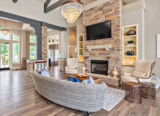 A living room with a stone fireplace and a grey couch.