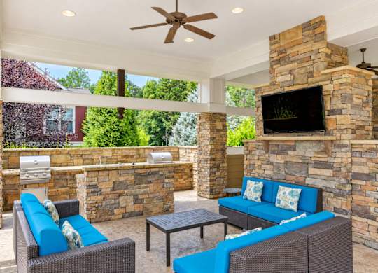 A patio with a blue couch and a stone fireplace.