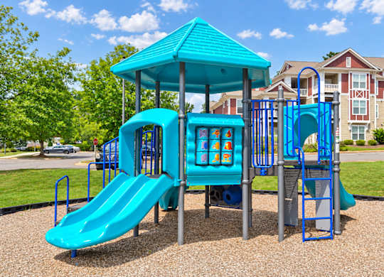 A playground with a blue slide and a blue roofed structure.