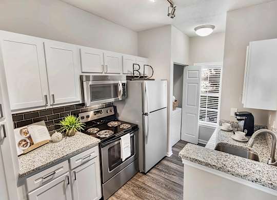 A kitchen with white cabinets and a granite countertop.