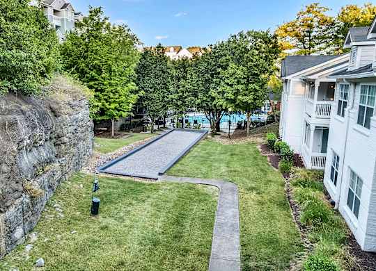 A stone wall with a green lawn in front of a white building.