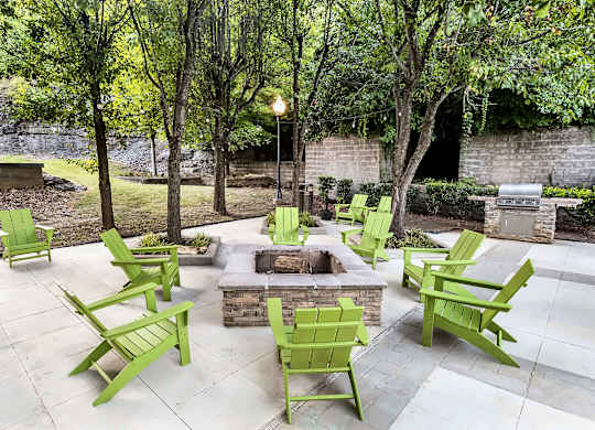 A patio with green chairs and a fire pit.
