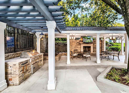 A covered outdoor patio with a fireplace and seating area.