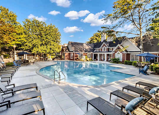 A large outdoor swimming pool surrounded by sun loungers and trees.