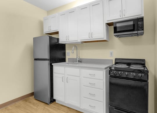 a kitchen with white cabinets and black appliances and a refrigerator