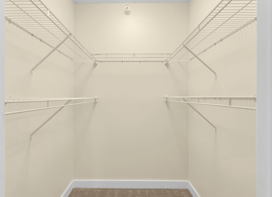 a spacious walk in closet in a home with white walls and empty shelves