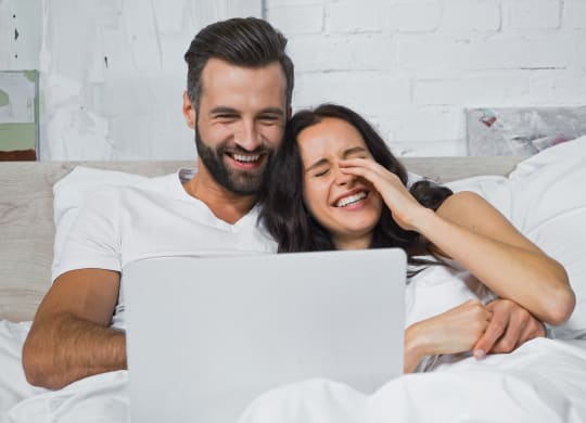 Couple watching movie on laptop and laughing