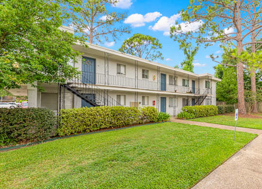 Apartment building with green lawn and trees in front.
