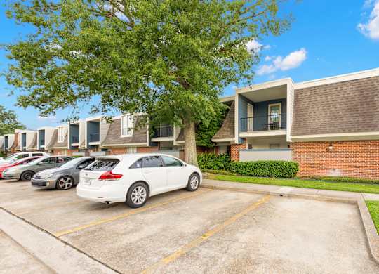 A white car is parked in a parking lot in front of a building.