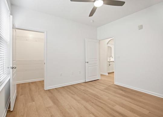 A room with a ceiling fan and wooden flooring.