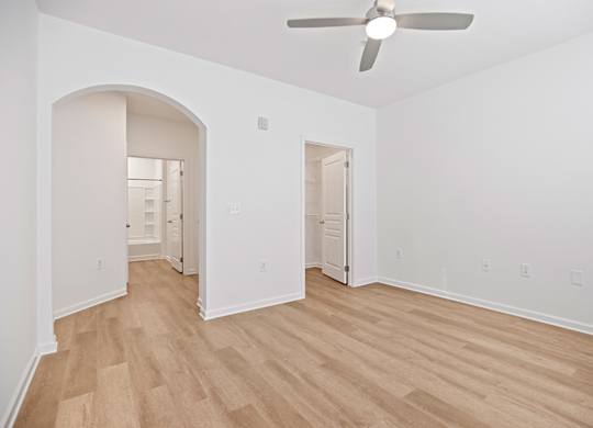 A room with a ceiling fan and wooden flooring.