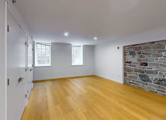 A room with wooden floors and a stone wall.
