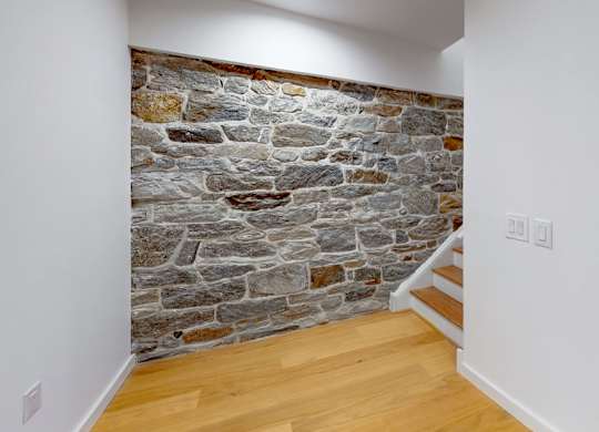 A stone wall with a wooden floor and white walls.