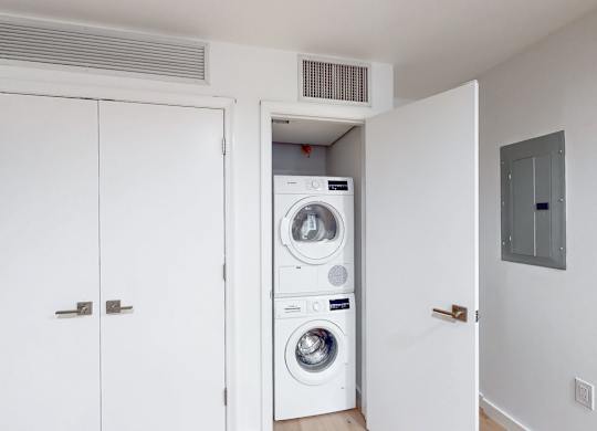A white door opens to a small laundry room with a washer and dryer.