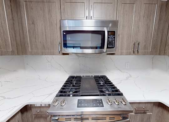 A modern kitchen with a stove top oven and microwave above it.