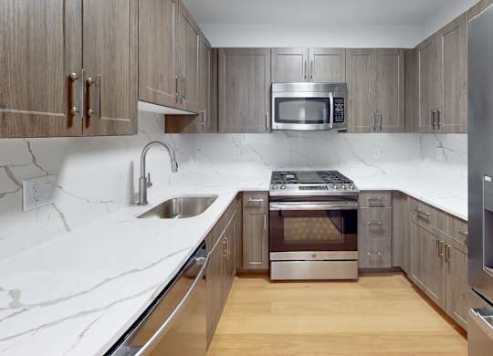 A modern kitchen with a marble countertop and stainless steel appliances.