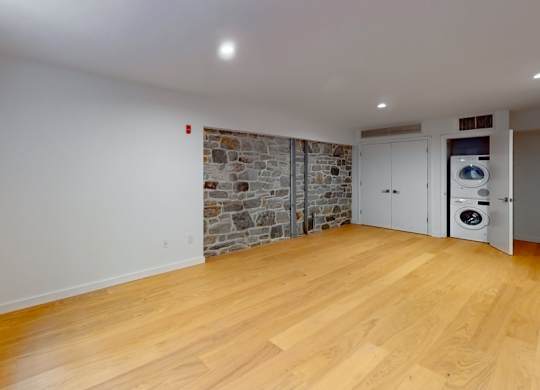 A room with wooden floors and a stone wall.