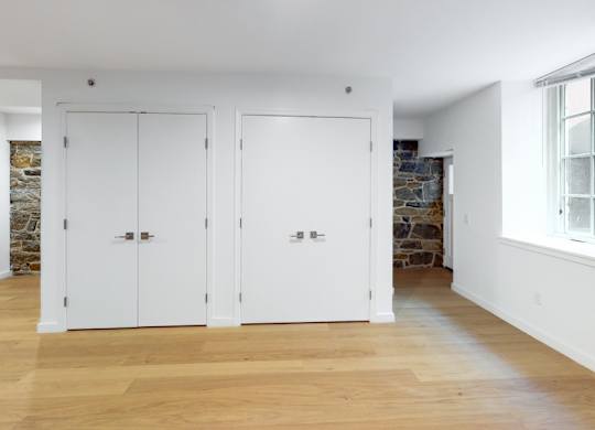 Three white doors are in a room with wood floors.
