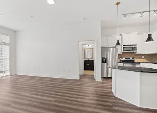 A kitchen with white cabinets and a wooden floor.
