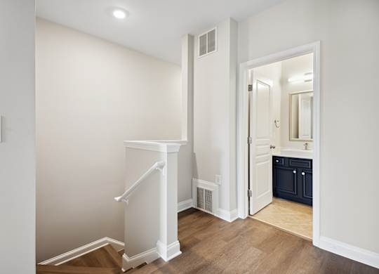 A white staircase with a landing in a room with a light switch on the wall.