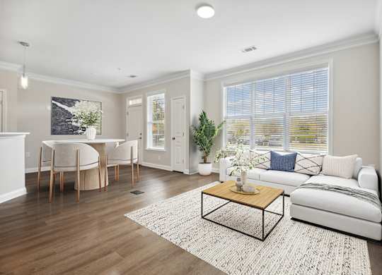 A living room with a white couch, a coffee table, and a dining table with chairs.