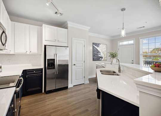 A modern kitchen with white cabinets and a black refrigerator.