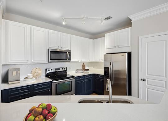 A kitchen with white cabinets and a bowl of apples on the counter.