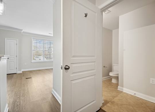 A white door is open to a room with a toilet.