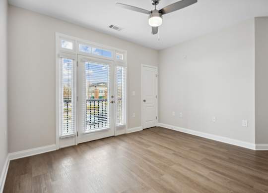 A room with a ceiling fan and a door leading to a balcony.