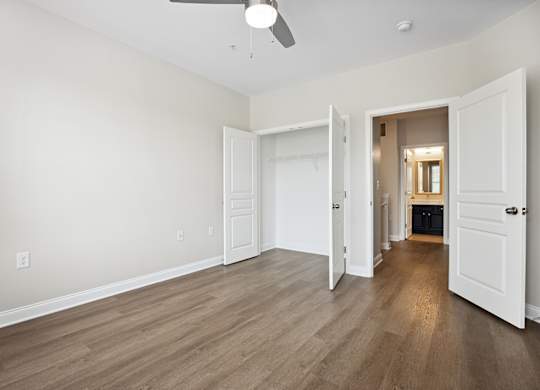 A room with a ceiling fan and light, and a doorway leading to another room.