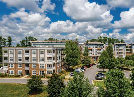 A large apartment complex with a parking lot in front.