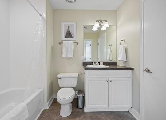 A white toilet sits in a bathroom next to a white bathtub.