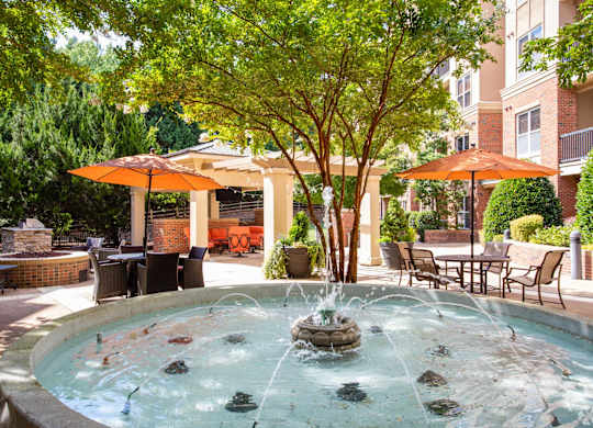 A fountain in the middle of a patio surrounded by chairs and umbrellas.