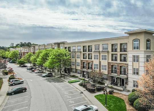 A street view of a row of apartment buildings with cars parked on the side of the road.