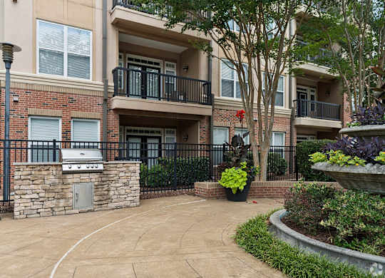 A brick building with a balcony and a small garden in front.