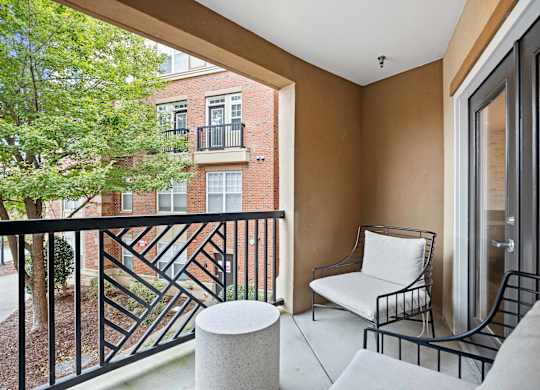 A balcony with a white chair and a black railing.